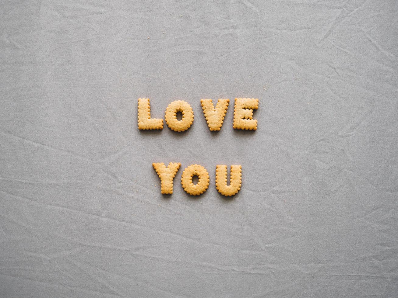 Bicuits arrange into words on grey background. Concept of word LOVE YOU. photo