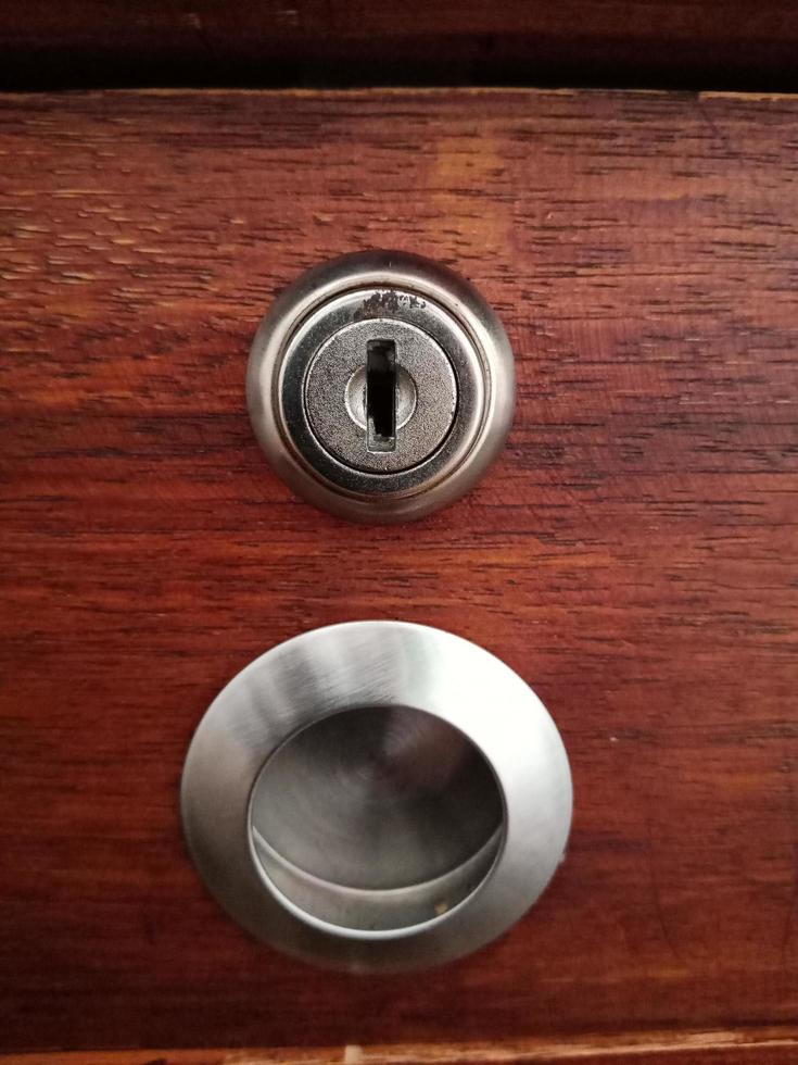 The keyhole on the drawer of wooden table photo