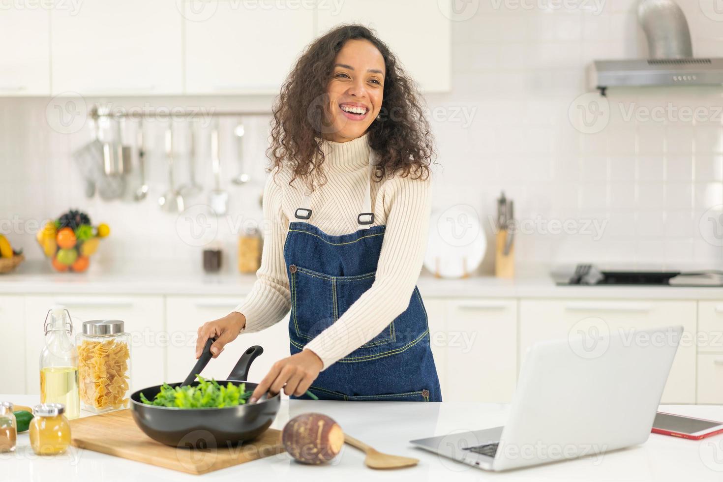 mujer latina grabando video y cocinando en la cocina foto