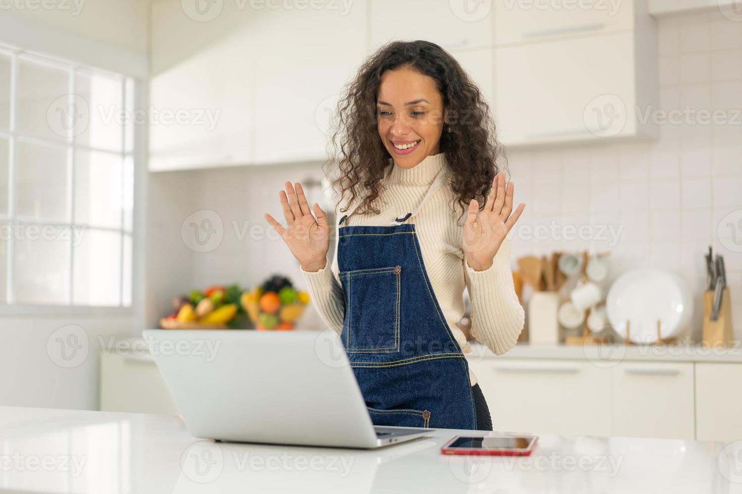 mujer latina grabando video y cocinando en la cocina foto