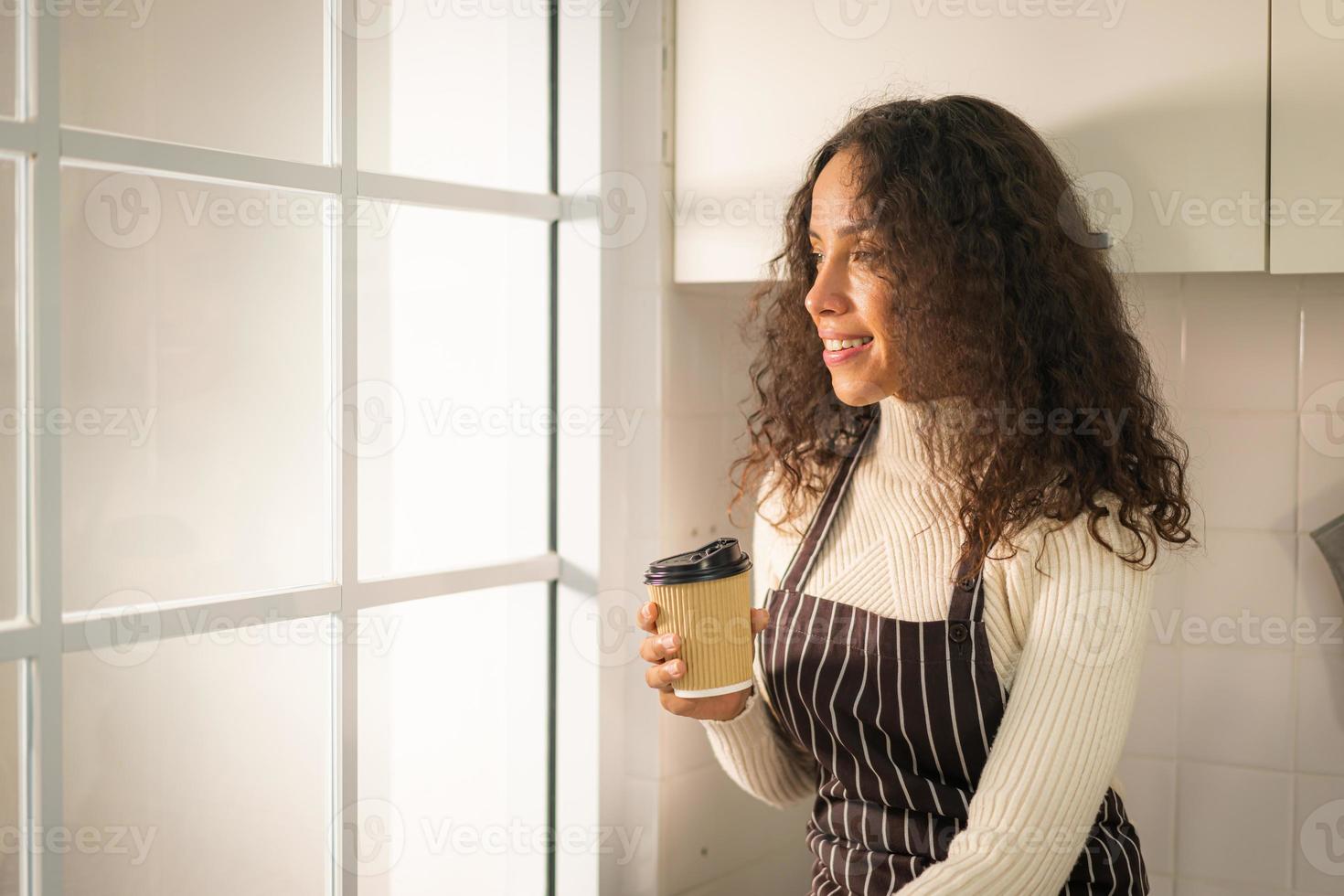 Latin woman drinking coffee in kitchen photo
