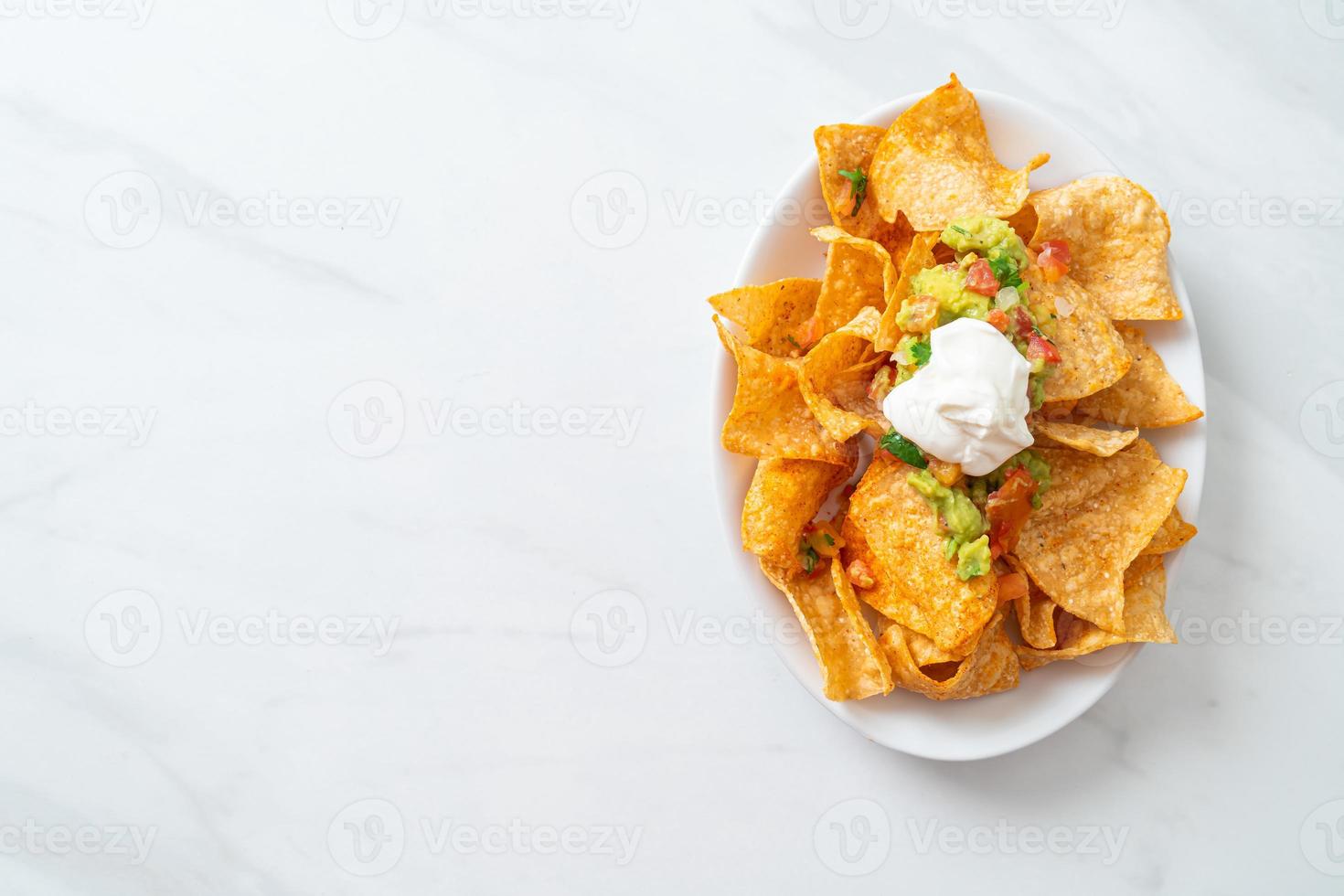 nachos chips de tortilla con jalapeño, guacamole, salsa de tomates y dip foto