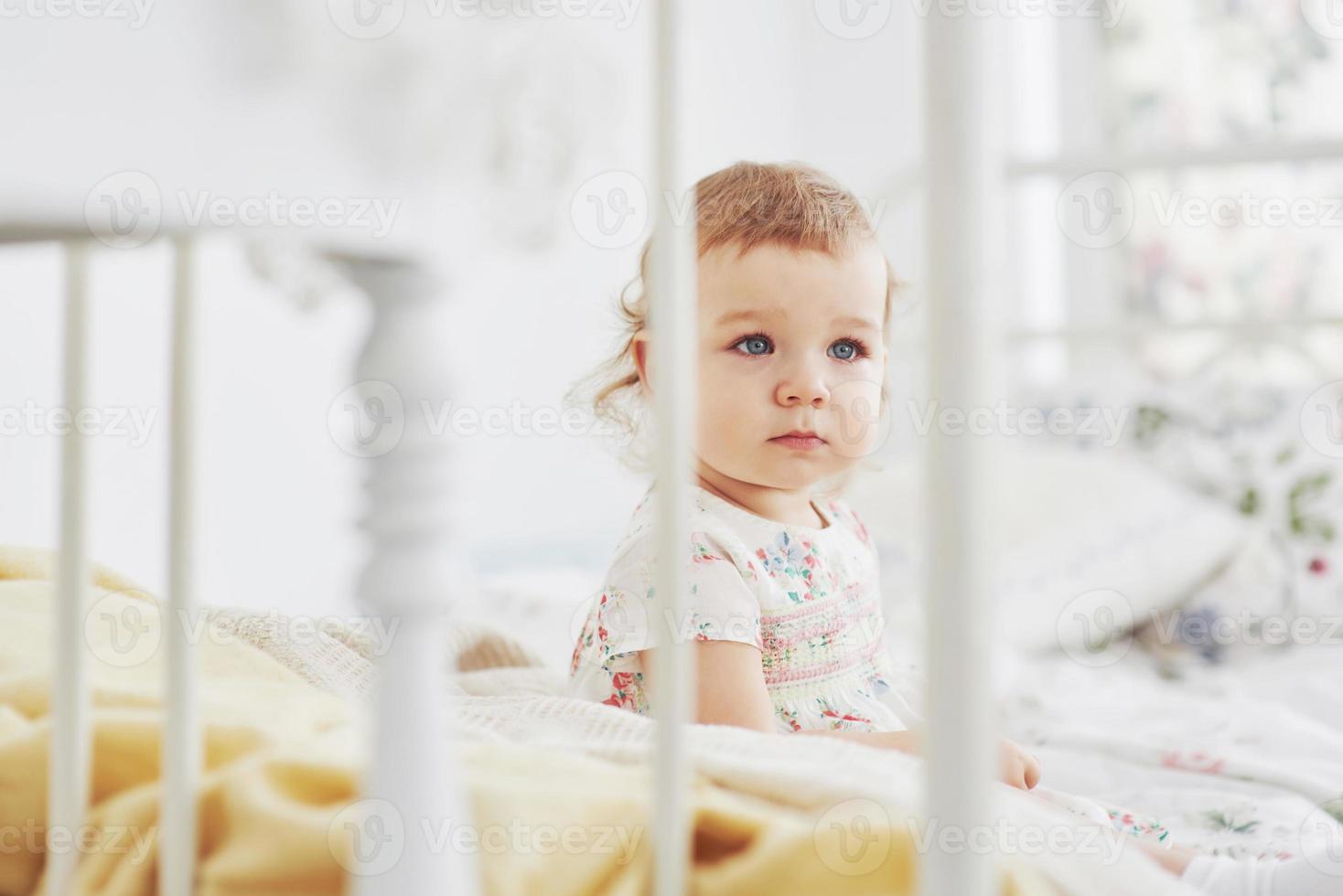 concepto de infancia. Niña en vestido lindo emplazamiento en la cama jugando con juguetes en el hogar foto