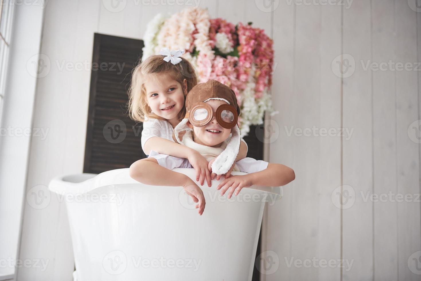 Portrait of a girl and a boy in pilot hat playing in bathroom at pilots or sailors. The concept of travel, childhood and the realization of dreams photo