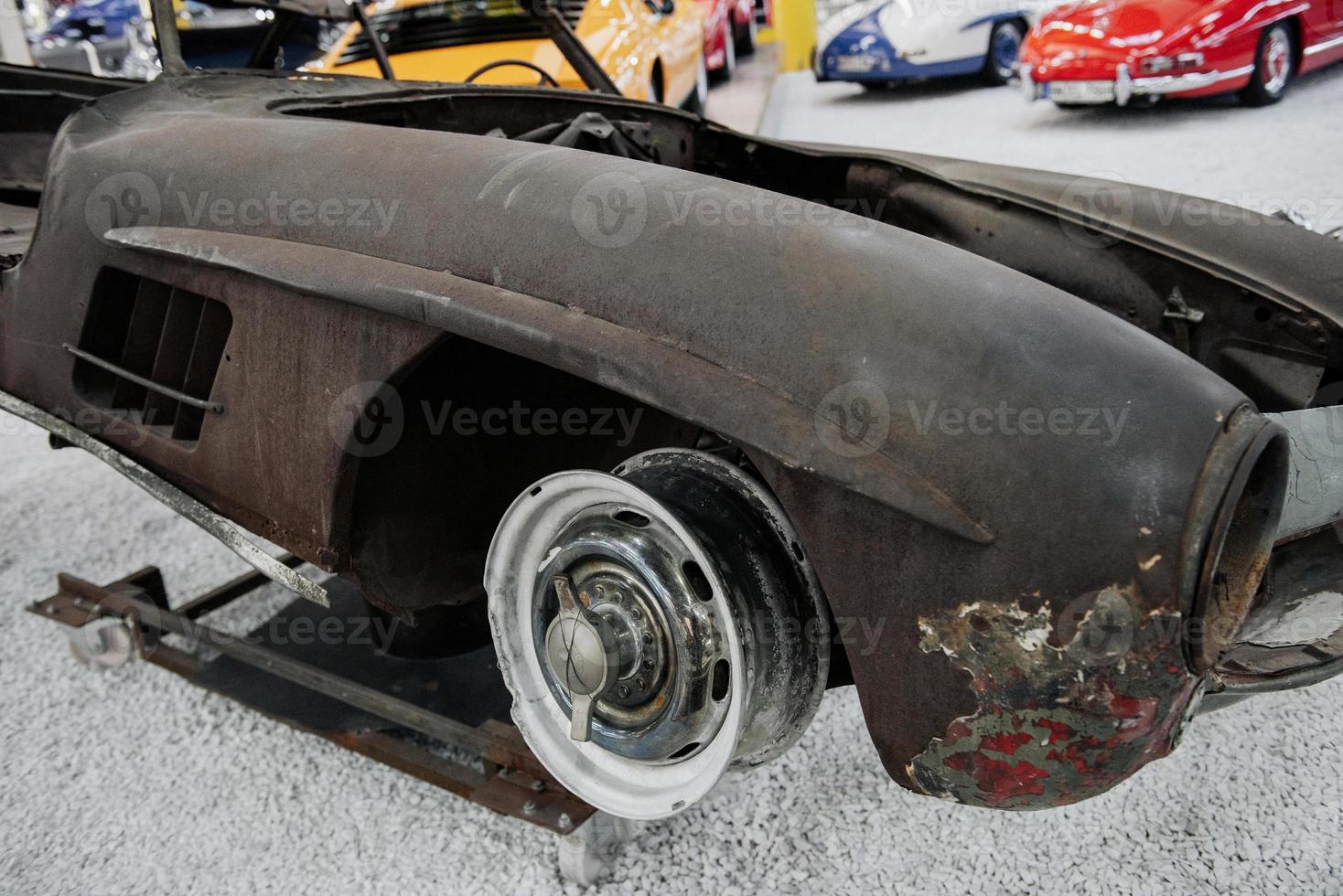 old rusty retro car bumper lies on the white rock surface in the auto show photo