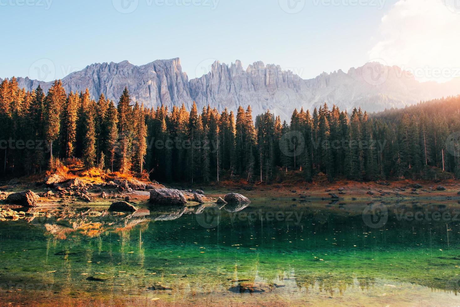 la luz del sol en los árboles. paisaje otoñal con lago claro, bosque de abetos y montañas majestuosas foto