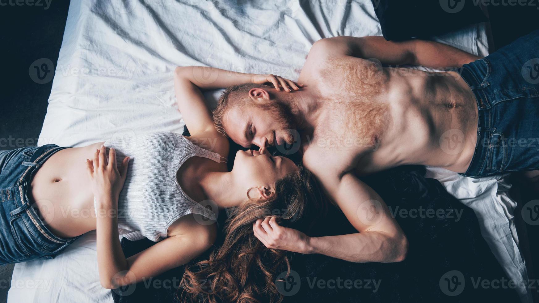 un retrato de una joven pareja feliz que se relaja en una cama acogedora foto