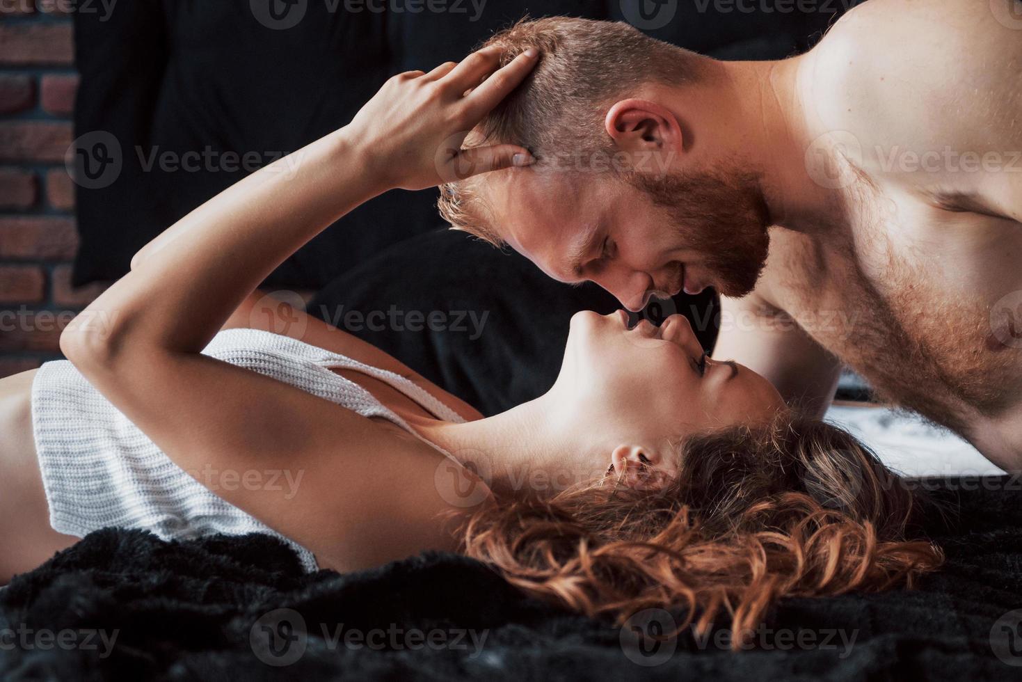 A portrait of a happy young couple who relax in a cozy bed photo