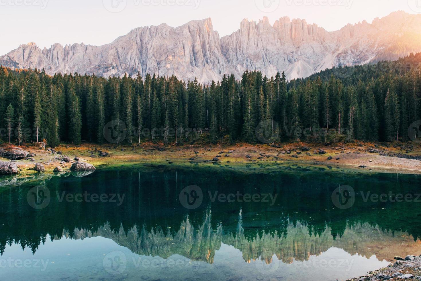 variedad de colores en el fondo y costa. paisaje otoñal con lago claro, bosque de abetos y montañas majestuosas foto