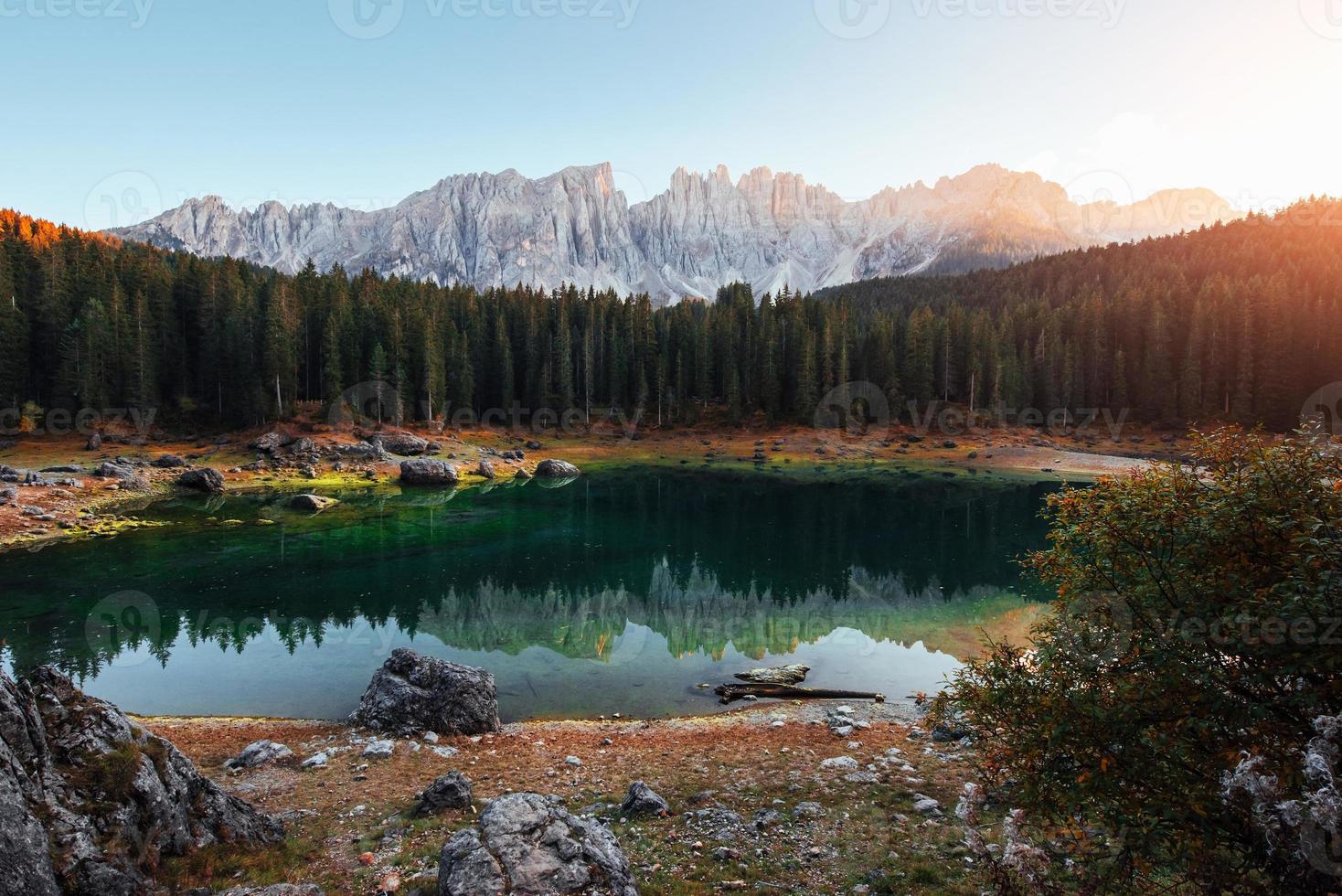 It's sunset time. Autumn landscape with clear lake, fir forest and majestic mountains photo