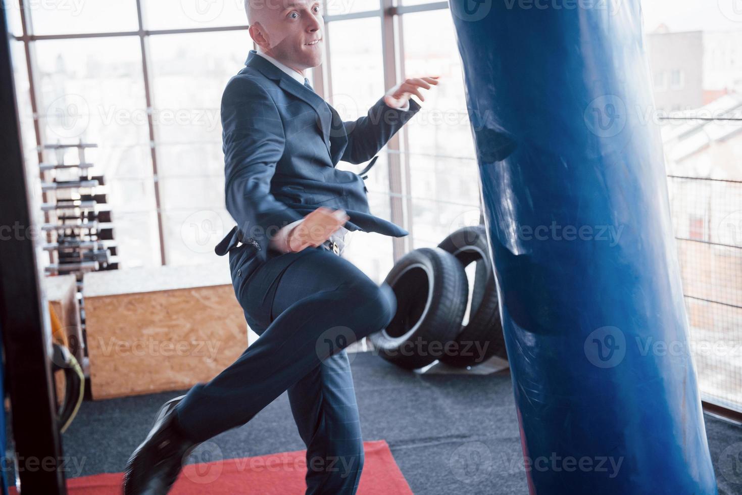 An angry bald businessman beats a boxing pear in the gym. concept of anger management photo