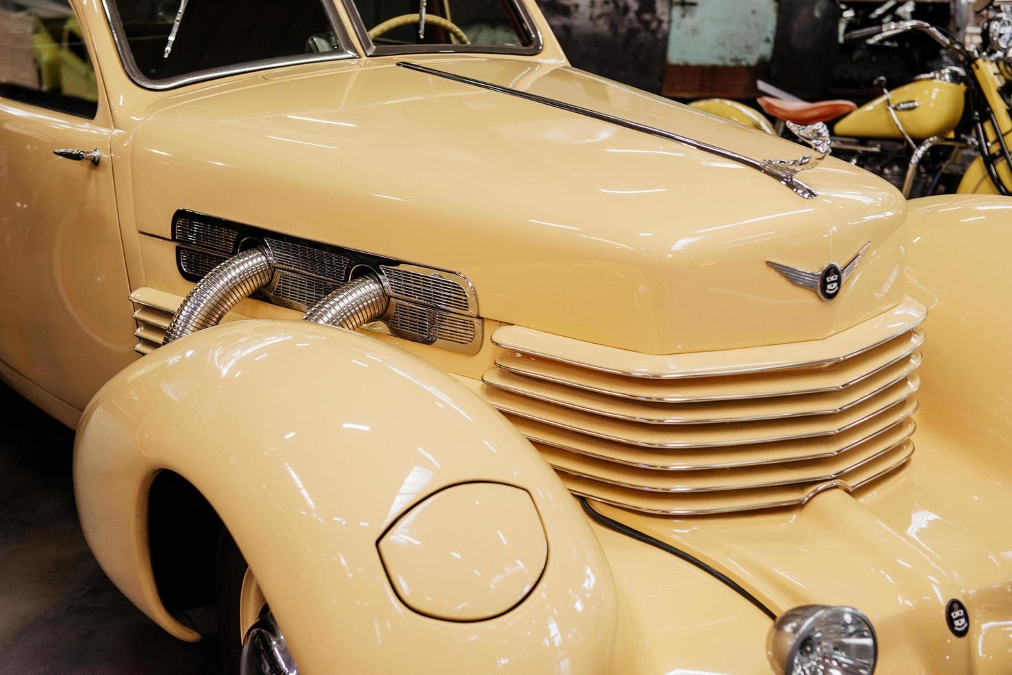 SINSHEIM, GERMANY - OCTOBER 16, 2018 Technik Museum. Right and front part of luxury creamy colored retro vehicle with motorbike at background photo