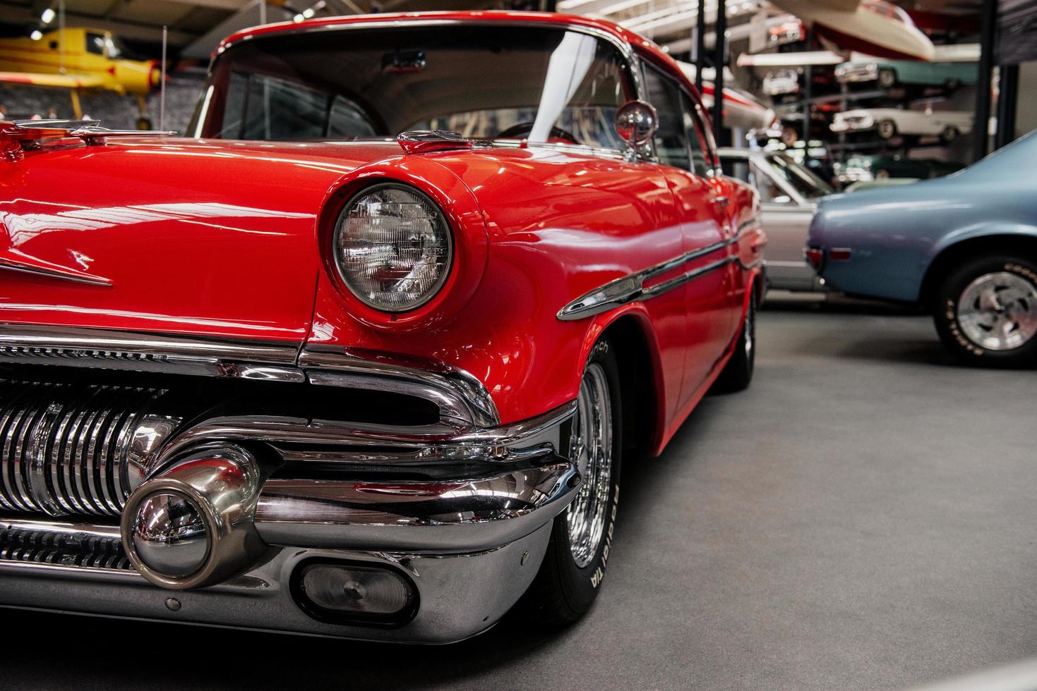 SINSHEIM, GERMANY - OCTOBER 16, 2018 Technik Museum. Red polished retro car parked with other vehicles on the ground and special stands at exhibition photo