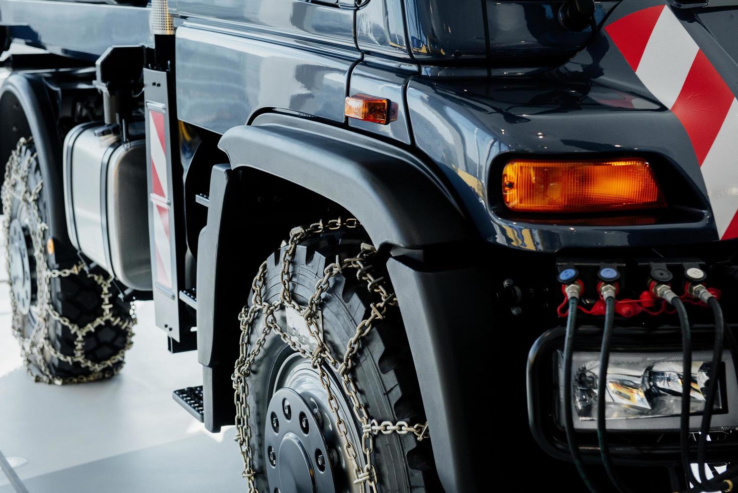 Cropped image. Right side of the car. Jeep with snow chains parked indoors at the white tile on vehicle show photo