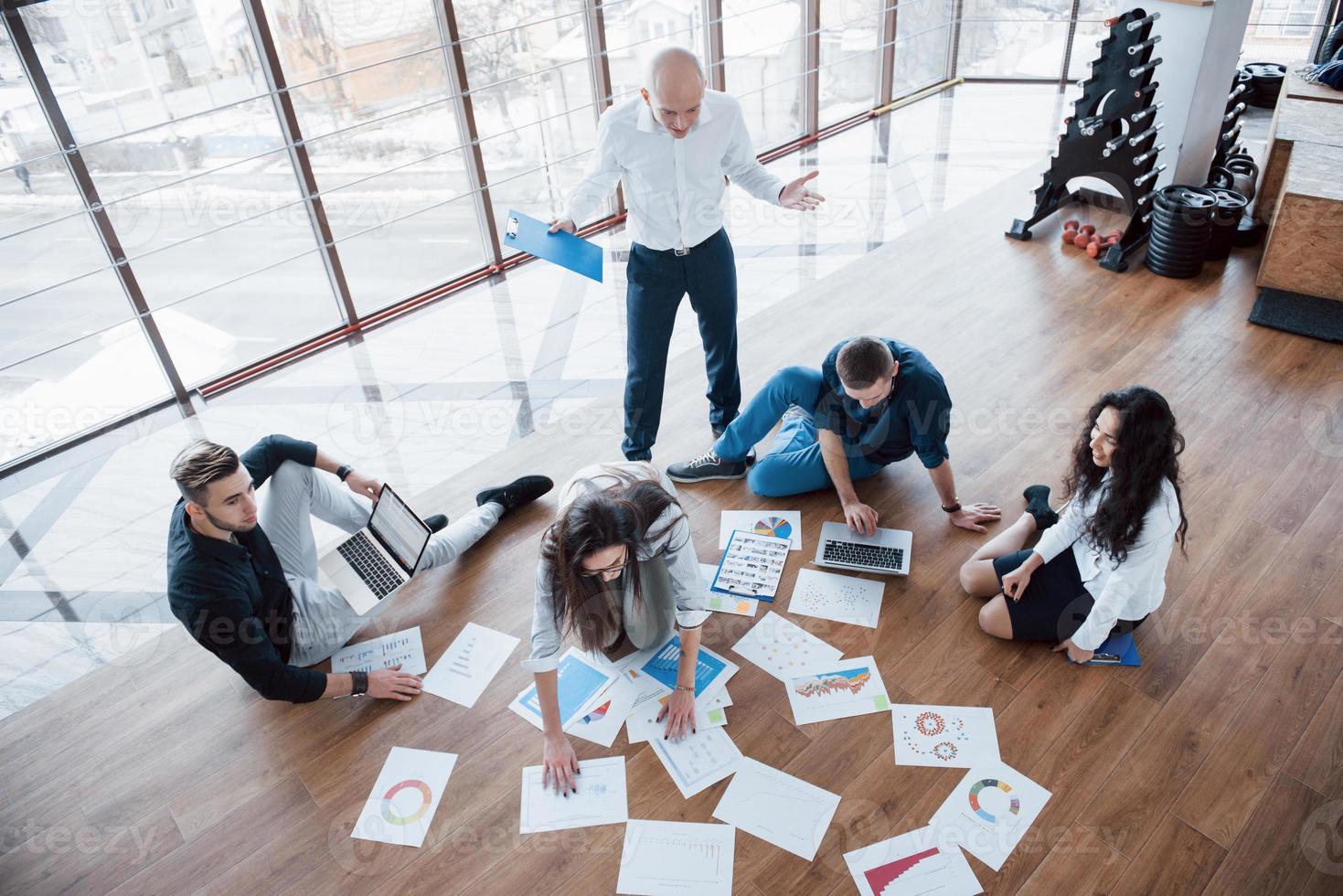 Planning strategy together. Business team looking at papers on floor in search of one idea. Cooperation corporate achievement and teamwork concept photo