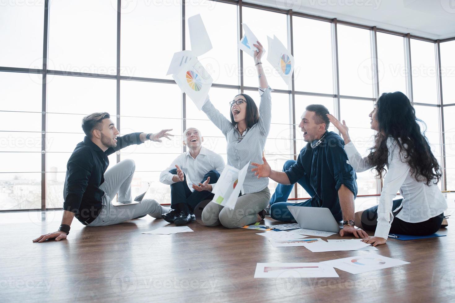 Success strategy together. Cheerful business colleagues tossing papers at creative office. Cooperation corporate achievement. Planning design draw. Teamwork concept photo