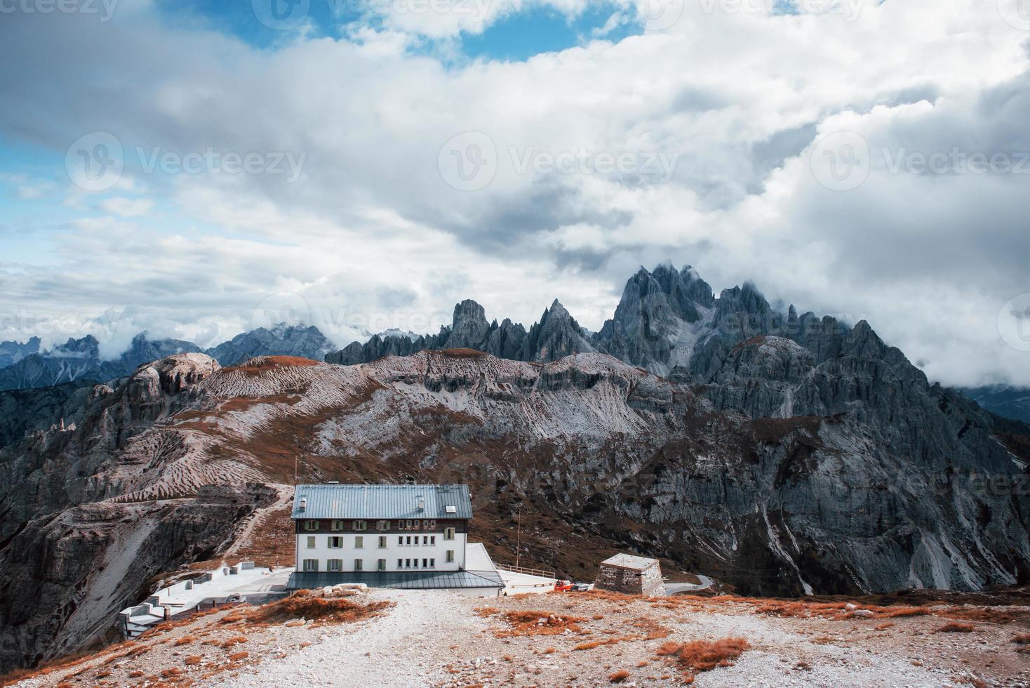 Building standing high on the mountains near the bunch of cliffs with mist and clouds photo