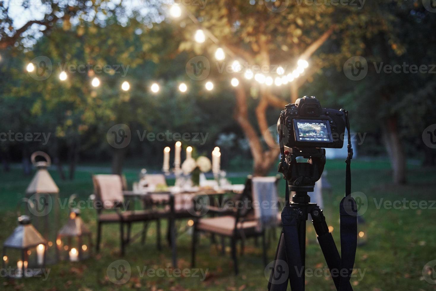 equipo profesional. Cámara en el soporte del trípode en el campo frente a la mesa preparada al atardecer foto