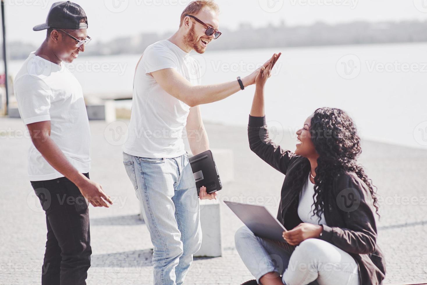 Beautiful multi ethnic friends using a laptop in the Street. Youth lifestyle concept photo