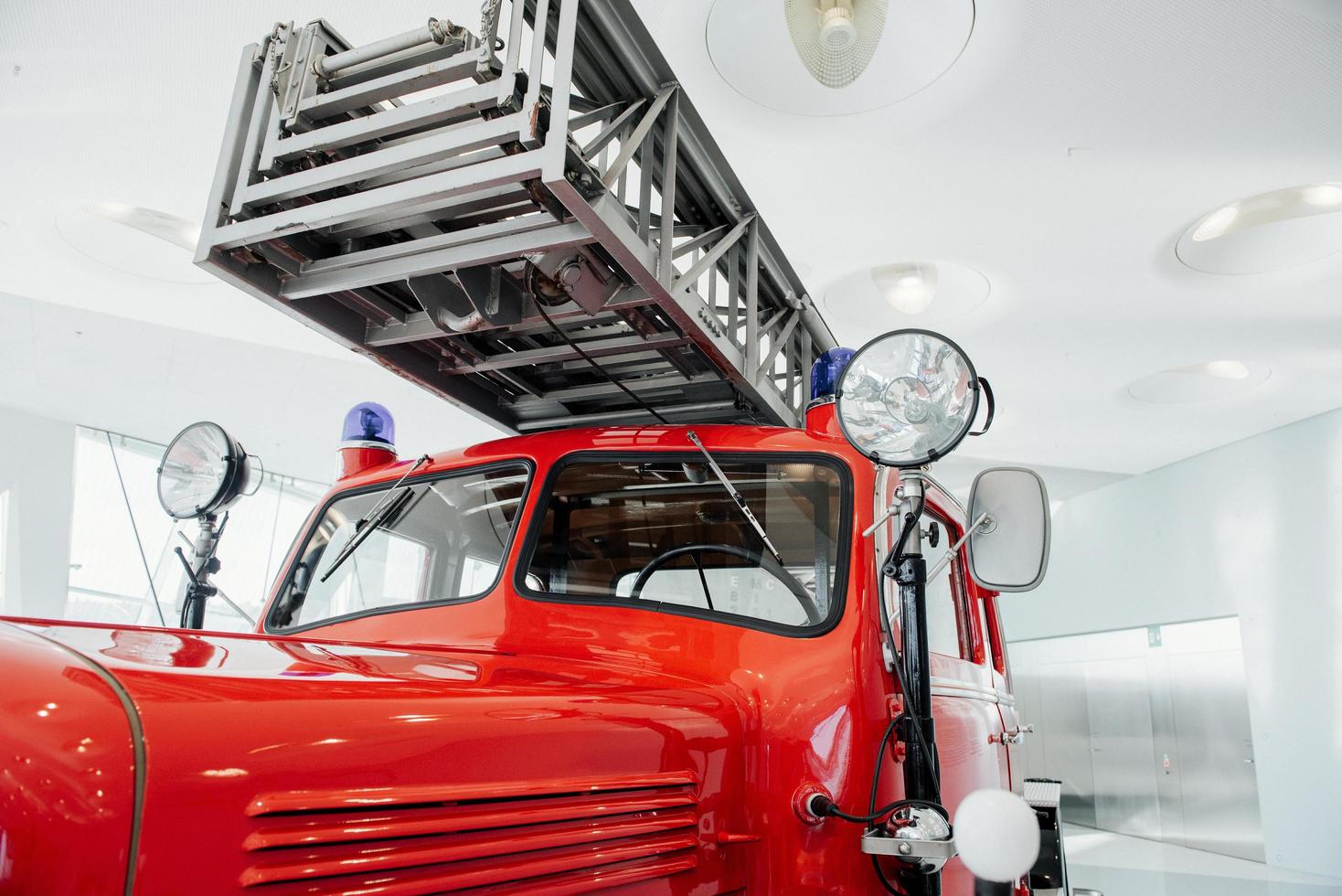 La escalera larga es una parte indispensable. Frente al camión de bomberos rojo pulido de pie en el interior de la exposición foto