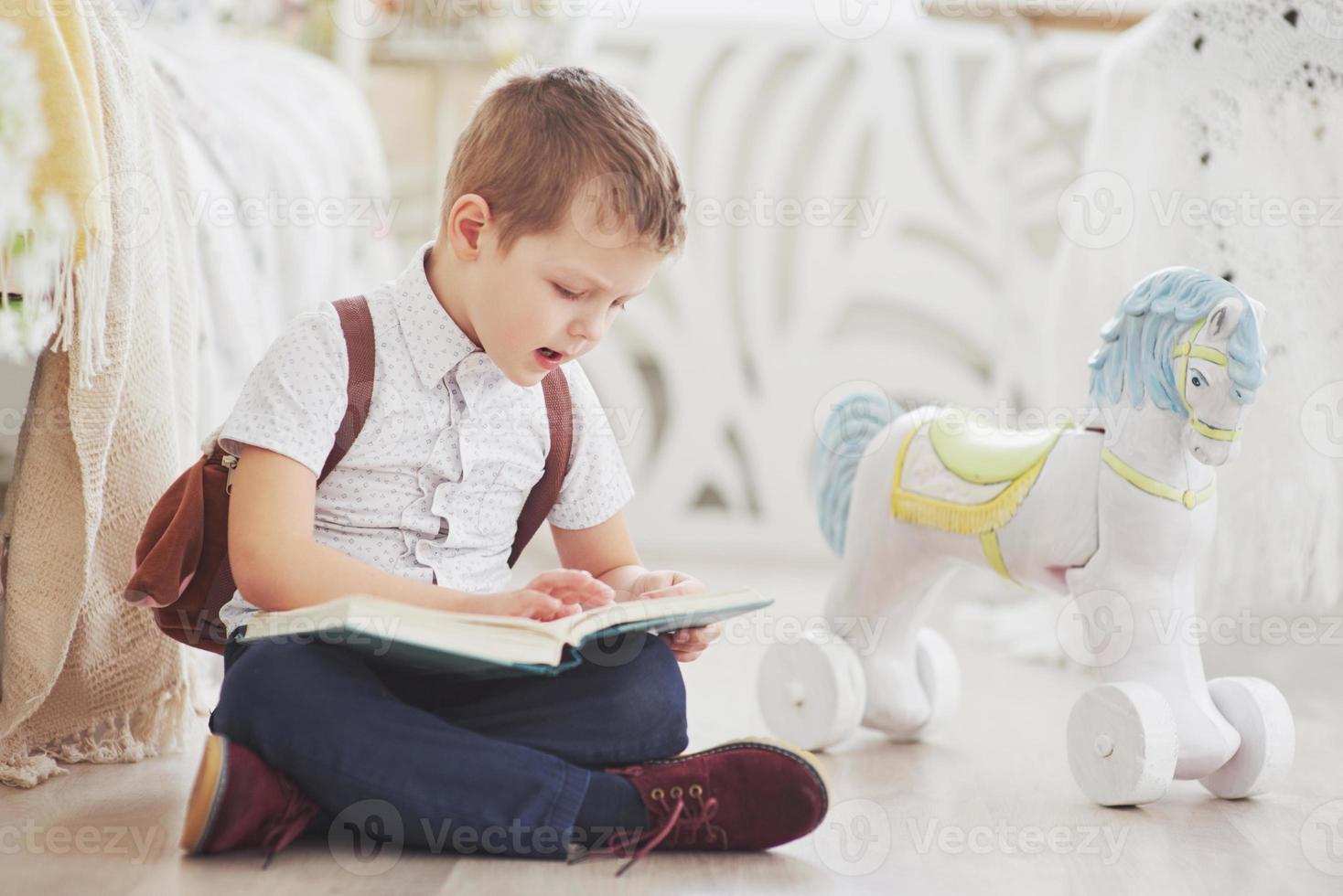 niño lindo va a la escuela por primera vez. niño con bolso y libro. niño hace un maletín, habitación infantil sobre un fondo foto