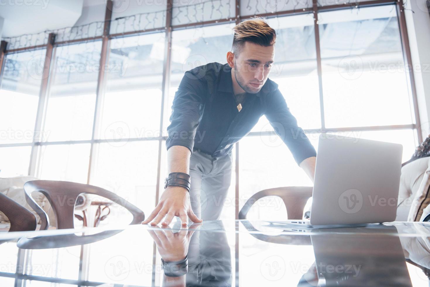 Concebido joven trabajando en la computadora portátil mientras está sentado en su lugar de trabajo en la oficina foto