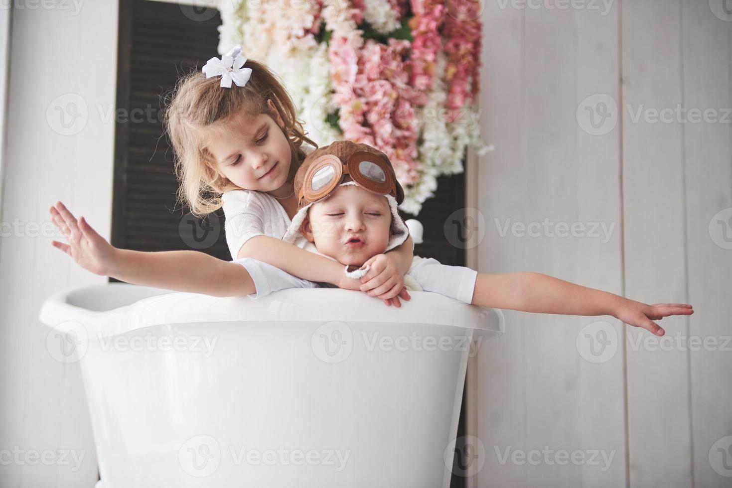 Portrait of a girl and a boy in pilot hat playing in bathroom at pilots or sailors. The concept of travel, childhood and the realization of dreams photo