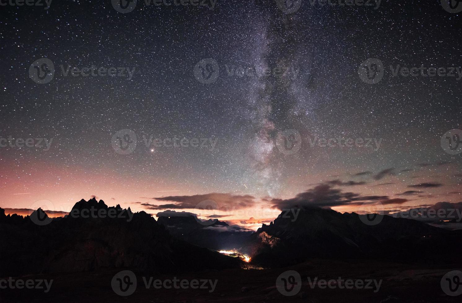 lugar tranquilo y atmosférico. hermoso espacio lleno de estrellas en el cielo. las montañas están rodeadas de una densa niebla foto