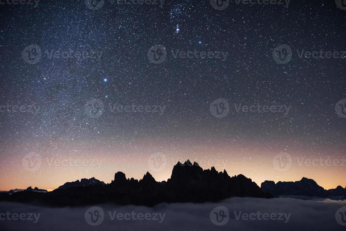 hermoso espacio lleno de estrellas en el cielo. las montañas están rodeadas de una densa niebla foto