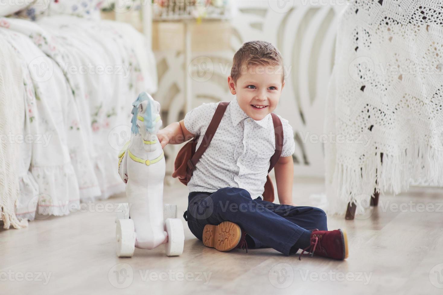 niño lindo va a la escuela por primera vez. niño con bolso y libro. niño hace un maletín, habitación infantil sobre un fondo foto