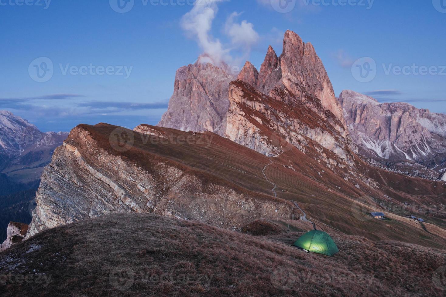 Big cliff. Green tent standing on the hill. Awesome place in the alpes of Seceda photo