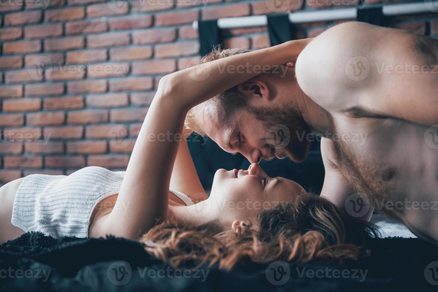 un retrato de una joven pareja feliz que se relaja en una cama acogedora foto