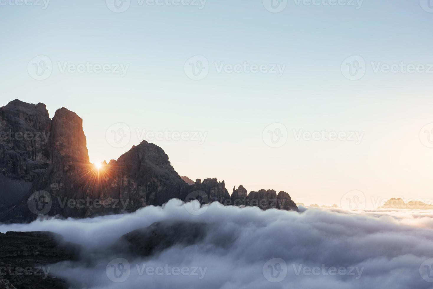 The light going from between the cliffs. Stunning sunset through the rocks filled with hard mist going on through photo