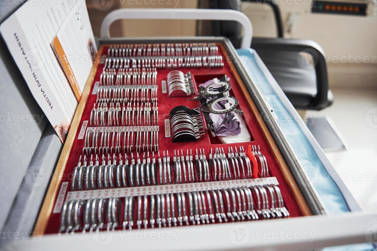 Red box lying on the table with ophthalmic device and many of the lenses photo