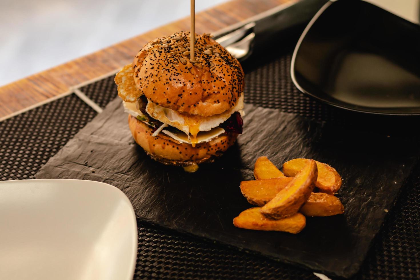 Hamburguesa con huevo y papas fritas servida en restaurante. foto