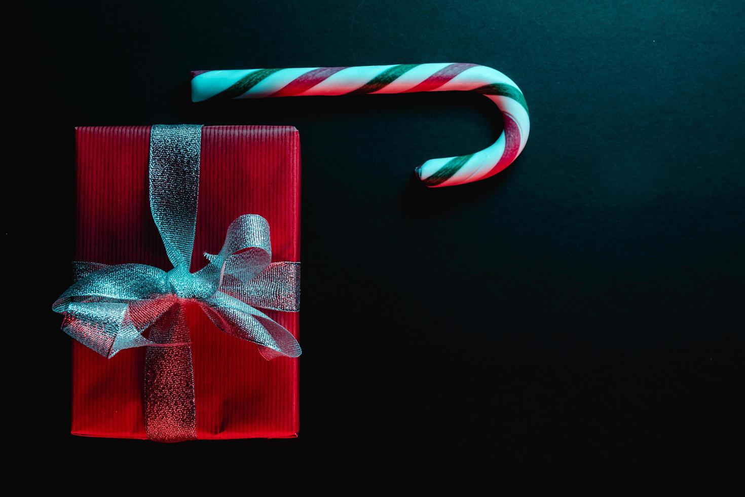 Minimal Christmas composition. Greeting card template with candy cane on dark background. photo