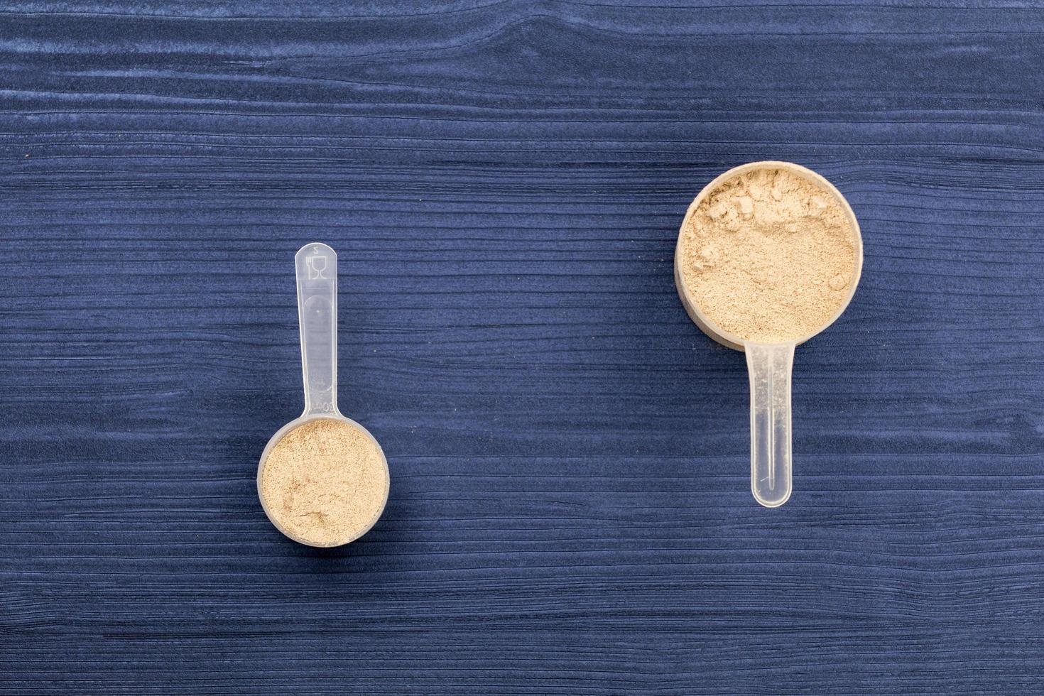 Bolas llenas de proteína en polvo sobre fondo de madera azul foto