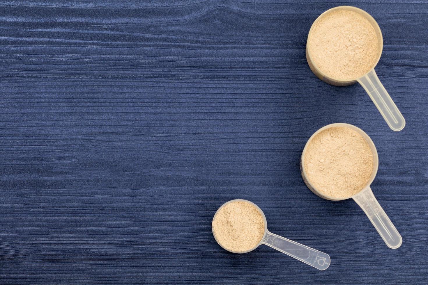 Bolas llenas de proteína en polvo sobre fondo de madera azul foto