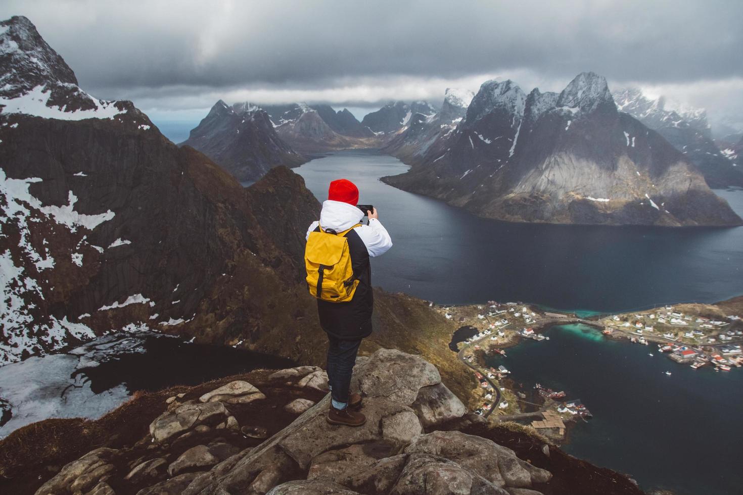 Man traveler taking photo with a smartphone hiking on Reinebringen mountain ridge in Norway lifestyle adventure traveling