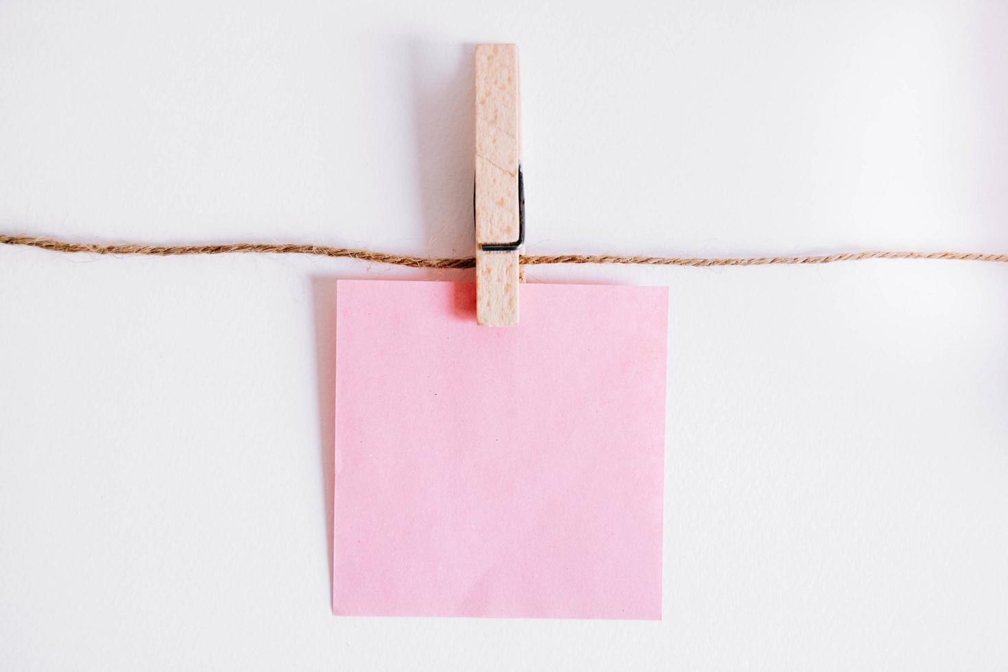 Pink stickers on clothesline with wooden clothespin on white background photo