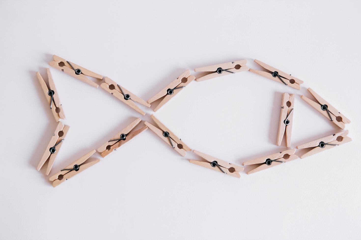 Wooden clothespins on a white background which are composed in the form of a fish icon photo