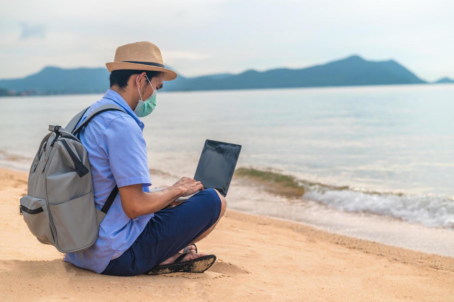 El hombre usa una máscara con un ordenador portátil en la playa, el mar y el hombre viajes vacaciones phuket sandbox Tailandia son la libertad financiera de la vida foto