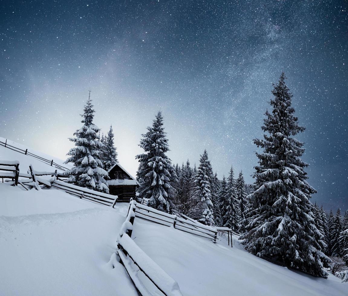 Winter landscape. Mountain village in the Ukrainian Carpathians. Vibrant night sky with stars and nebula and galaxy. Deep sky astrophoto photo