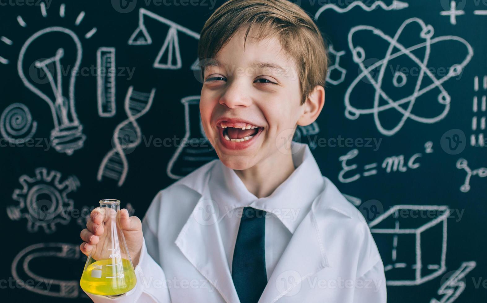 Niño feliz riendo y mostrando líquido en matraz foto