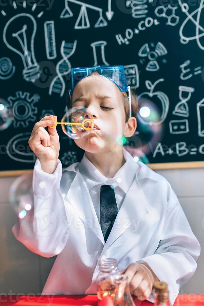 Kid doing soap bubbles against of drawn blackboard photo