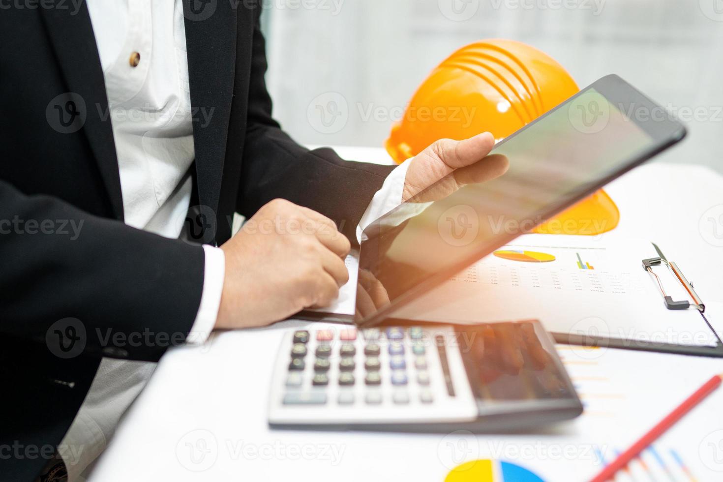 Architect or engineer working project accounting with graph and construction helmet in office, Construction account concept. photo