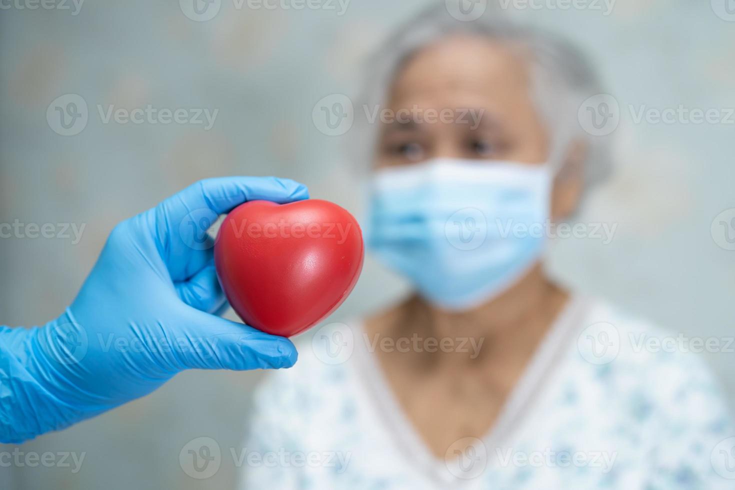 El médico le da un corazón rojo al paciente asiático mayor o anciano, concepto médico fuerte y saludable foto