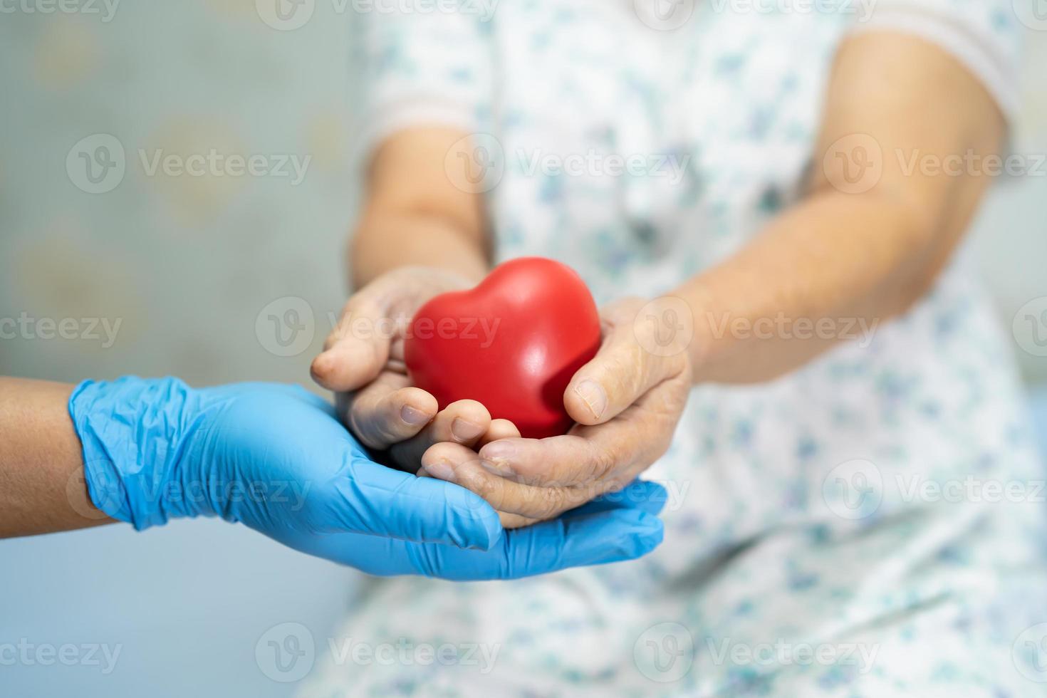 El médico le da un corazón rojo al paciente asiático mayor o anciano, concepto médico fuerte y saludable foto
