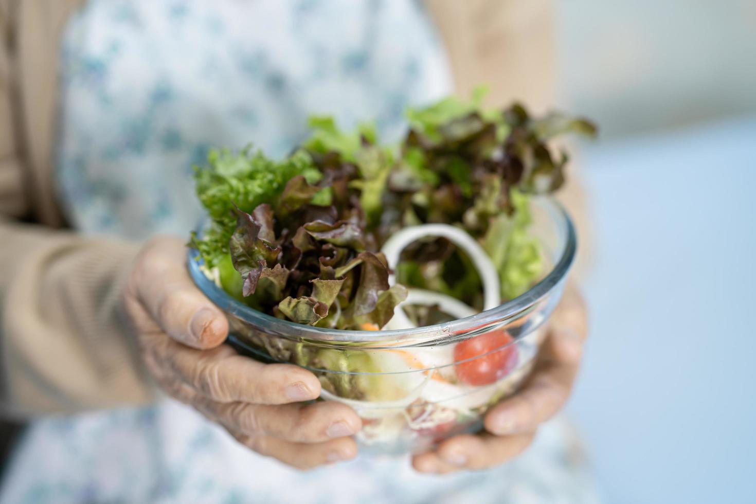 Asian senior or elderly old lady woman patient eating breakfast vegetable healthy food with hope and happy while sitting and hungry on bed in hospital. photo