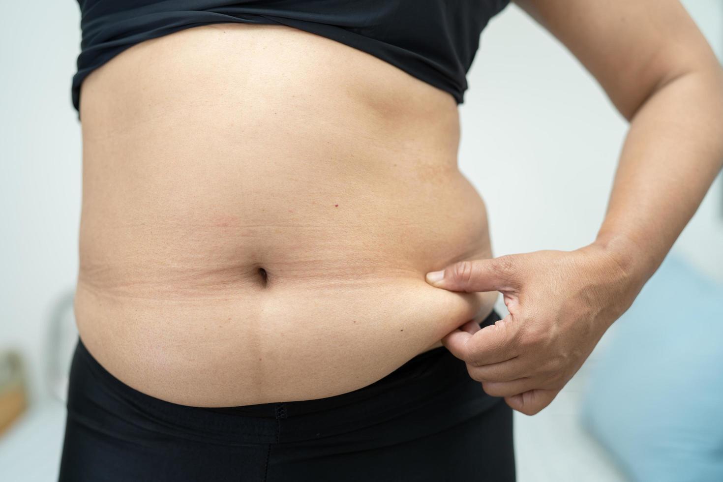 Overweight Asian woman show fat belly at office. photo